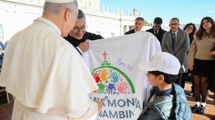 ĐTC Lêô XIV nhận lá cờ cùng với logo chính thức của Ngày Thế giới Trẻ em 2026 từ bé Majd Bernard và Cha Enzo Fortunato, ngày 19.11.2025.