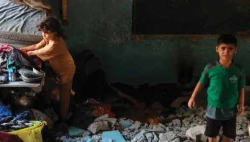 Trẻ em Palestine di tản đang nhặt lại một số đồ đạc gia đình giữa đống đổ nát