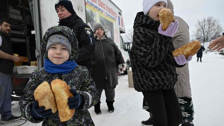 Trẻ em Ucraina nhận bánh mì được phân phát cho người di cư